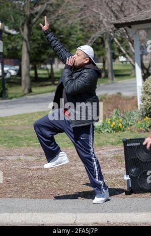 Un uomo conduce una lezione di Zumba attraverso un vigoroso allenamento di danza in un parco a Queens, New York City. Foto Stock