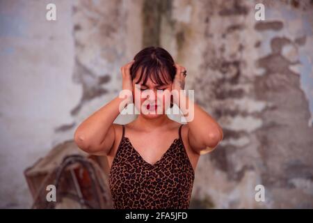 Ritratto di preoccupata bella donna bruna giovane stressata che soffre di emicrania, mani sulla testa che guardano verso il basso. Copia spazio, persone. Foto Stock