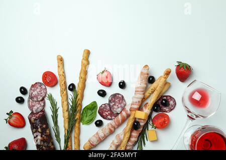 Grissini con pancetta, spuntini e vino su sfondo bianco Foto Stock