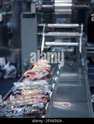 Confezionamento automatico della macchina impacchettatrice a cuscino per prodotti da forno. Macchina confezionatrice per pane, toast, panini e materie plastiche sulla linea di produzione di prodotti da forno Foto Stock