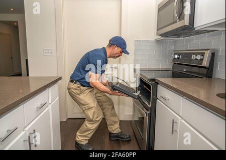 Tecnico dell'apparecchio rimozione di uno sportello del forno per la riparazione in un casa Foto Stock