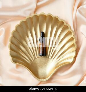 Contagocce bottiglia di vetro ambrato su fondale di seta color pesca. Disposizione piatta, vista dall'alto. Foto Stock