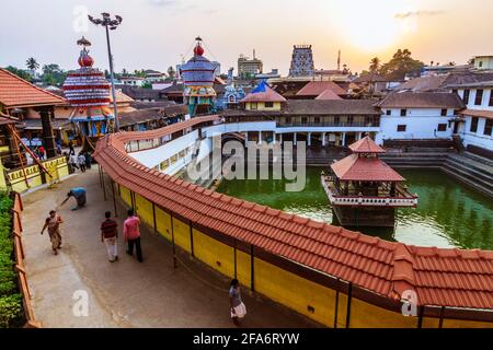 Udupi, Karnataka, India : la gente cammina al tramonto intorno al serbatoio d'acqua di Madhva Sarovara adiacente al tempio di Krishna 13 ° secolo fondato dal locale Foto Stock