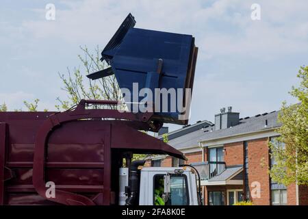 Il camion della spazzatura si prepara a prendere in bidoni della spazzatura all'interno della raccolta dei rifiuti nei cortili degli edifici residenziali. Foto Stock