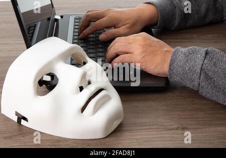 Ladro hacker in maschera rubare le informazioni personali dal computer portatile. Hacking concettuale. Foto Stock