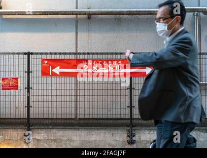 Tokyo. 23 Apr 2021. Un uomo passa accanto a un banner di divaricamento sociale a Tokyo, Giappone, il 23 aprile 2021. Il primo ministro giapponese Yoshihide Suga venerdì ha dichiarato un terzo stato di emergenza sulla COVID-19 a Tokyo, Osaka, Kyoto e Hyogo. Lo stato di emergenza entrerà in vigore da domenica a maggio 11. Credit: Christopher Jue/Xinhua/Alamy Live News Foto Stock