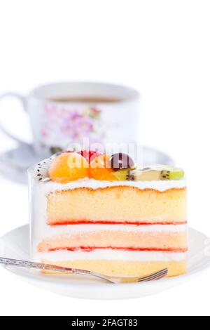 Fetta di torta bella su piatto con frutta fresca sopra e una tazza di caffè, isolato su sfondo bianco Foto Stock