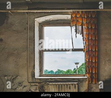 Edificio intemperie con tenda danneggiata appesa alla finestra invecchiata Foto Stock