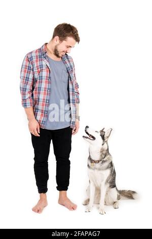 Giovane uomo bearded che si stese con il suo cane Husky. Hipster maschio con camicia a scacchi in flanella e canotta grigia trascorrere del tempo di qualità con quattro l. Foto Stock