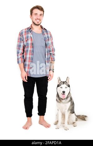 Giovane uomo bearded che si stese con il suo cane Husky. Hipster maschio con camicia a scacchi in flanella e canotta grigia trascorrere del tempo di qualità con quattro l. Foto Stock