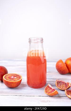 Bottiglia fatta in casa di limonata di arance sanguinose, frutta rinfrescante acqua su uno sfondo di legno bianco, primo piano. Foto Stock