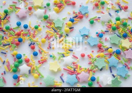 Sfondo festivo multicolore di una dispersione di caramelle zuccherate per cupcakes, altri dolci sotto forma di stelle, bastoni e palle. Colori pastello Foto Stock