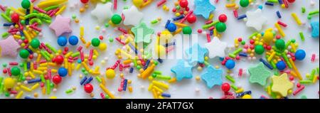 Striscione con sfondo festivo multicolore di una dispersione di caramelle zuccherate per cupcakes e altri dolci sotto forma di stelle, bastoni e palle. Foto Stock