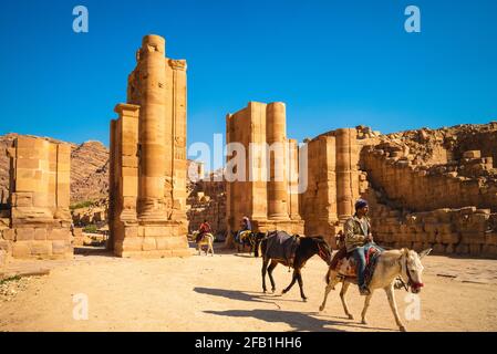 22 marzo 2019: Un uomo che cavalcava un asino attraverso la porta Adriana, nota anche come la porta Temenos, situata alla fine della via colonnata a petra, giordania. Fai Foto Stock