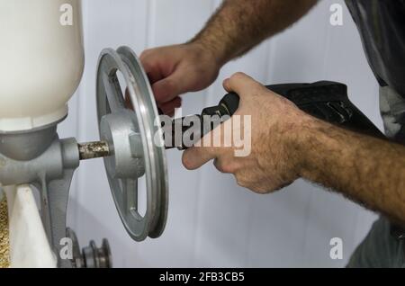 Homebrewer che imposta un mulino di malto per macinare con l'aiuto di un trapano. Foto Stock
