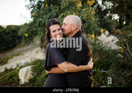 Marito hugging & Kissing moglie nel giardino di San Diego Foto Stock