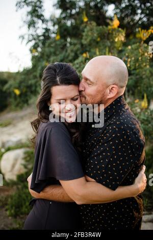 Marito hugging & Kissing moglie nel giardino di San Diego Foto Stock