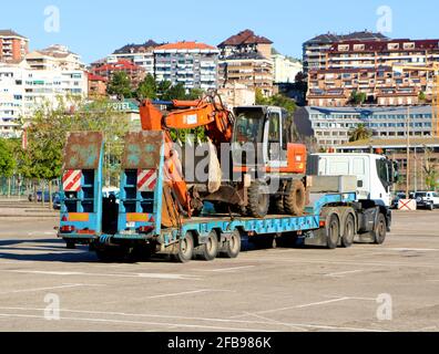 Un scavatore meccanico caricato su un rimorchio del camion nel parcheggio del randello di calcio Santander Santander Cantabria Spagna Sunny primavera mattina Foto Stock