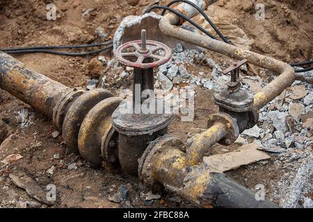 un uomo che lavora in uniforme è impegnato nella riparazione del tubo del gas, la riparazione dell'apparecchiatura con gli attrezzi, la riparazione delle comunicazioni del ferro gasman, migliorandone Foto Stock