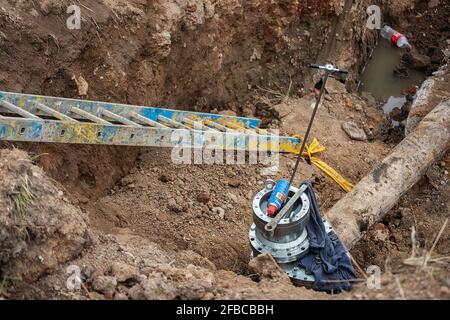 un uomo che lavora in uniforme è impegnato nella riparazione del tubo del gas, la riparazione dell'apparecchiatura con gli attrezzi, la riparazione delle comunicazioni del ferro gasman, migliorandone Foto Stock