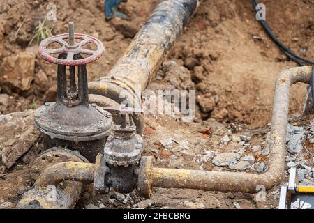 un uomo che lavora in uniforme è impegnato nella riparazione del tubo del gas, la riparazione dell'apparecchiatura con gli attrezzi, la riparazione delle comunicazioni del ferro gasman, migliorandone Foto Stock