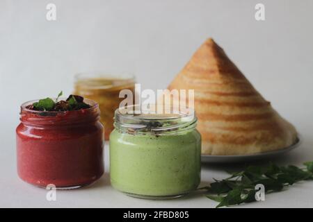 Pancake croccante fatto di riso e lenticchie ripiegate a forma di cono. Servito con condimenti speziati di barbabietola di cocco, condimenti di coriandolo di cocco e sambar Foto Stock