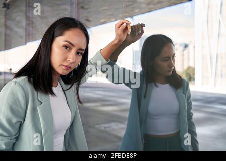 Imprenditrice femminile appoggiata su una parete di vetro Foto Stock
