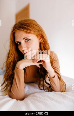 Donna rossa attraente con sdraiato sul letto a casa Foto Stock