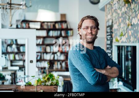 Uomo sicuro proprietario con le braccia incrociate al bar Foto Stock