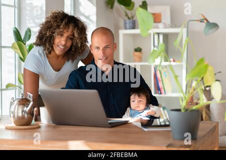 Madre, padre e figlia che guardano il computer portatile a casa Foto Stock