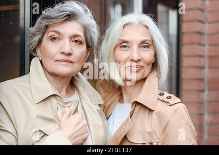 Le amiche mature indossano cappotti di trincea Foto Stock