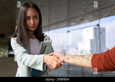 Bella donna d'affari fiduciosa scuotendo la mano con la collega femminile Foto Stock