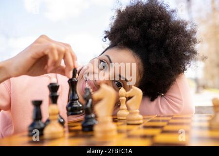 Donna afro che gioca a scacchi sul tavolo Foto Stock