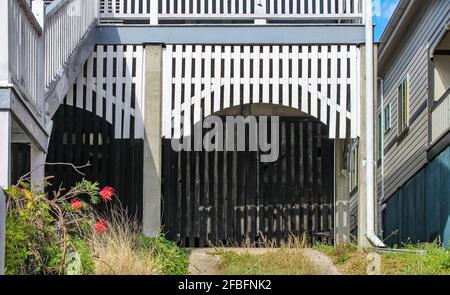 Closeup di carport-garage sotto una casa Queenslander con tavole bianche in un arco e vialetto diviso Foto Stock