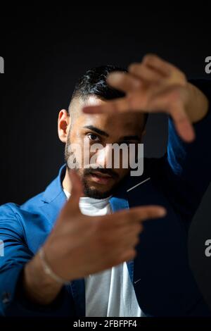 Bell'uomo che mostra la cornice del dito su sfondo nero Foto Stock