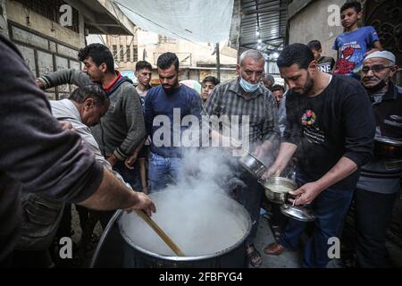 Gaza, Palestina. 23 Apr 2021. Il Palestinese Walid al-Hattab (indossando una camicia di plaid) distribuisce il cibo libero alle famiglie povere durante il mese santo di Ramadan nel quartiere di Shejaiya nella città di Gaza. Credit: SOPA Images Limited/Alamy Live News Foto Stock