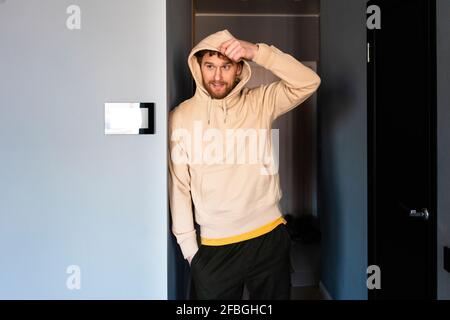 Uomo che indossa il cappuccio mentre si è in piedi alla porta Foto Stock