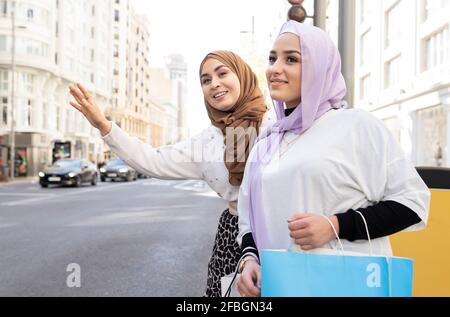 Le donne arabe salutano il taxi mentre si trovano in città Foto Stock