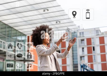Donna d'affari che utilizza un tablet digitale trasparente con icone all'aperto Foto Stock