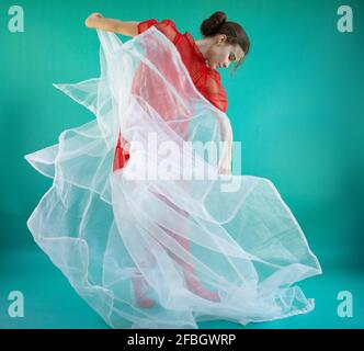 Giovane ballerina danzante con tulle bianco su sfondo turchese Foto Stock