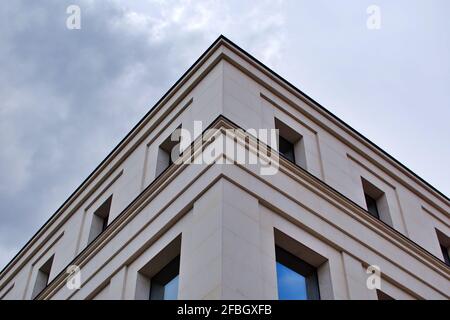 Facciata dell'edificio. Angolo di casa con finestre ai bordi contro il cielo tempestoso Foto Stock