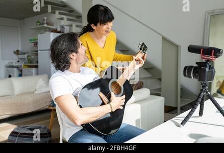 Accoppia il vlogging mentre suona la chitarra a casa Foto Stock