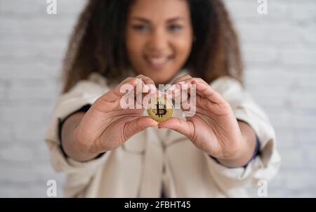 Donna sorridente che tiene bitcoin Foto Stock