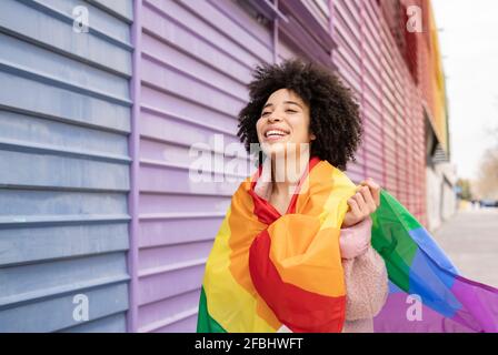 Donna allegra avvolta in bandiera arcobaleno Foto Stock