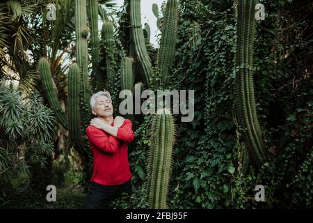 Uomo maturo che tocca il viso mentre si trova sotto un albero fiorente in giardino Foto Stock