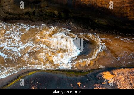Vista dall'alto delle onde schiumose sotto la luce del sole Foto Stock