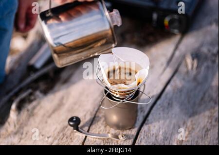 Uomo che versa l'acqua nel bollitore mentre prepara il caffè Foto Stock