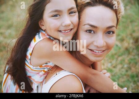 Madre sorridente che dà il giro del piggyback alla figlia Foto Stock