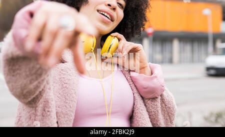 Giovane donna con giacca e cuffie che gesturano mentre cantano Foto Stock