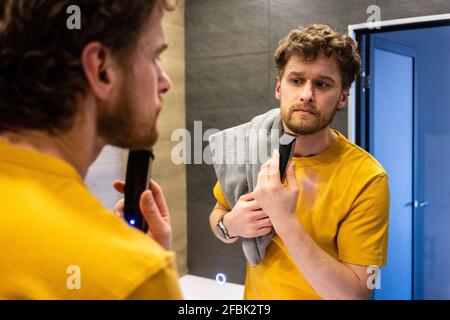 Barba per uomo con rasoio elettrico in bagno Foto Stock